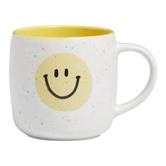 a yellow and white mug with a smiley face on it