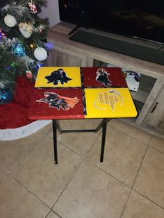 a table with three different colored tables on it and a christmas tree in the background