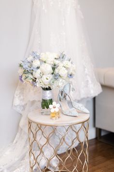 a table with flowers and shoes on it in front of a wedding dress hanger