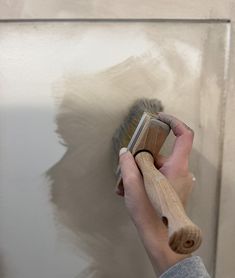 a person using a brush to paint a wall with white and gray colors on it