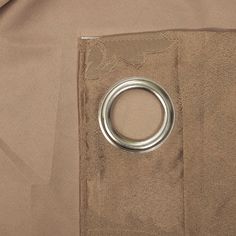 a close up of a metal ring in the pocket of a tan jacket with a brown background