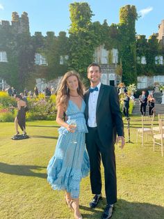 a man in a tuxedo standing next to a woman in a blue dress