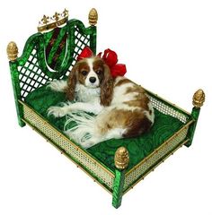 a brown and white dog laying on top of a green bed with a red bow