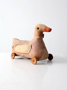 a wooden toy duck sitting on top of a white table