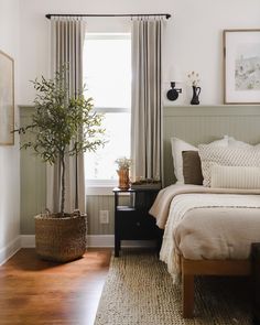 a bedroom with a bed, window and rug on the floor in front of it