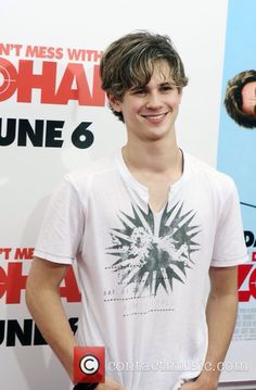 a young man standing in front of a poster