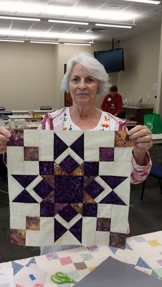 an older woman holding up a piece of quilt