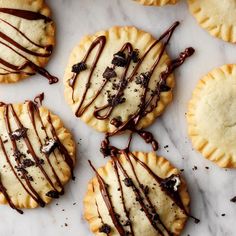 several cookies with chocolate drizzled on them sitting on a marble counter top