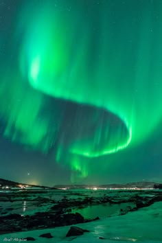 an aurora bore is seen in the sky above some snow and ice covered ground at night