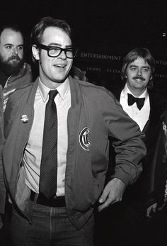 black and white photograph of three men in suits, one with glasses on his face