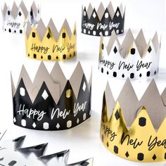 four crowns with happy new year written on them, all in black and gold paper