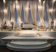 a wedding stage with white flowers on the steps and chandeliers hanging from the ceiling