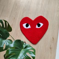 a heart shaped rug with eyes on the floor next to a potted monster plant