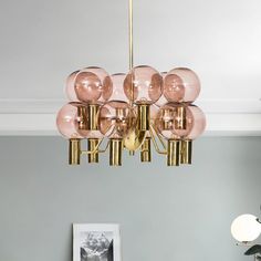 a chandelier hanging from the ceiling in a living room with pink and gold accents