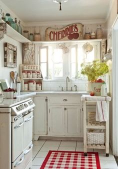 a white kitchen with red and white checkered rugs on the floor next to an oven