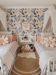 two twin beds in a bedroom with floral wallpaper on the walls and rugs