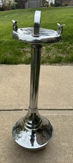 a close up of a metal object on the ground in front of a grass field