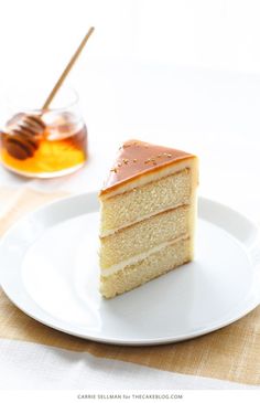 a piece of cake sitting on top of a white plate next to a honey cup