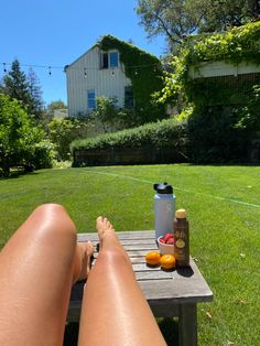 a woman laying on top of a wooden table next to a bottle of beer and oranges