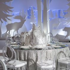 the table is set with clear plastic chairs and an elaborate centerpiece in the shape of a tree