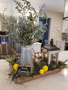 a vase filled with greenery and lemons on top of a kitchen counter