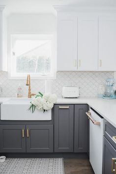 a kitchen with gray cabinets and white counter tops, gold pulls on the faucet