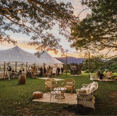 an outdoor tent set up for a party with chairs and tables in the foreground