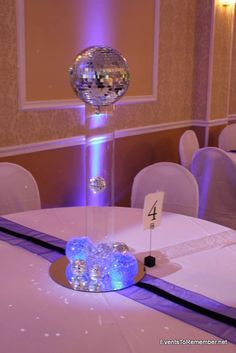 the table is set up for a party with disco ball centerpieces on it