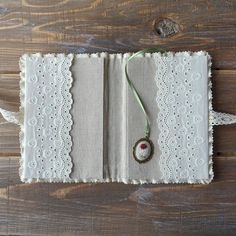 an open book with a button on the front and lace around it, sitting on a wooden surface