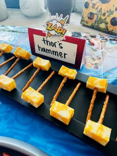 cheese skewers are arranged on a black tray with blue table cloth and sign that says thor's hammer