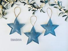 three blue stars hanging from strings on a white surface