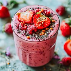 a smoothie with strawberries and chia seeds on the top is garnished with fruit