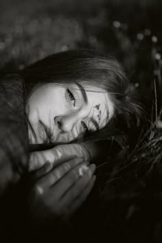 a black and white photo of a woman laying in the grass with her eyes closed