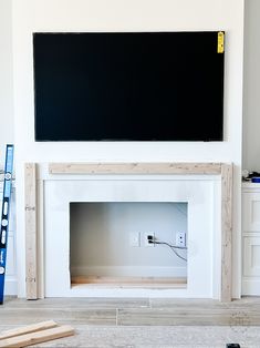 a white fireplace with a black screen above it and some tools on the floor next to it