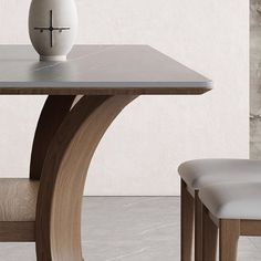 a white vase sitting on top of a table next to a wooden bench and chair