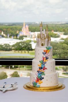 a wedding cake is on top of a table with a view of the city behind it