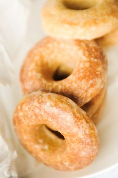 three donuts sitting on top of a white plate next to some waxed doughnuts