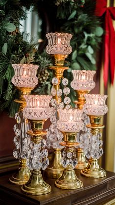 several glass candlesticks sitting on top of a table next to a christmas wreath