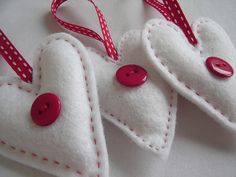 three felt heart ornaments with red buttons on them