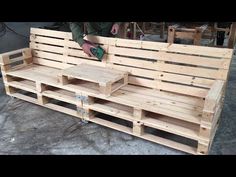 a wooden bench made out of pallets with a person working on the back end