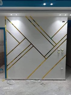 a white and gold wall in a room with lights on the ceiling is being worked on