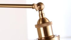 a close up view of a gold colored metal faucet on a white wall