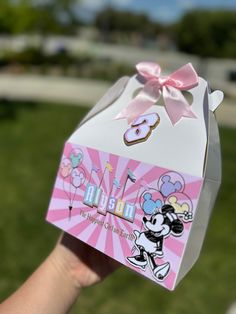 a person holding up a box with a minnie mouse sticker on it's side