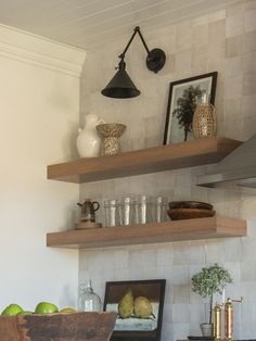 two open shelves in a kitchen with apples on the counter and other items below them