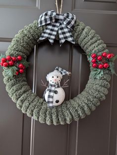 a christmas wreath with a snowman and holly on it hanging from the front door