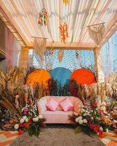 a pink couch sitting under a canopy covered in flowers and plants on top of a rug