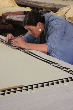 a woman laying on top of a white table next to a black and white rug