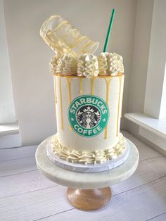 there is a starbucks cake on top of a stand with a green straw in it