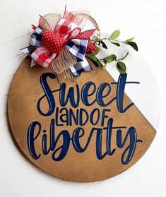 a wooden sign that says sweet land of liberty on the side of a white wall