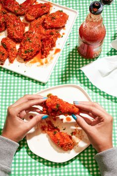 two people are eating chicken wings on a plate